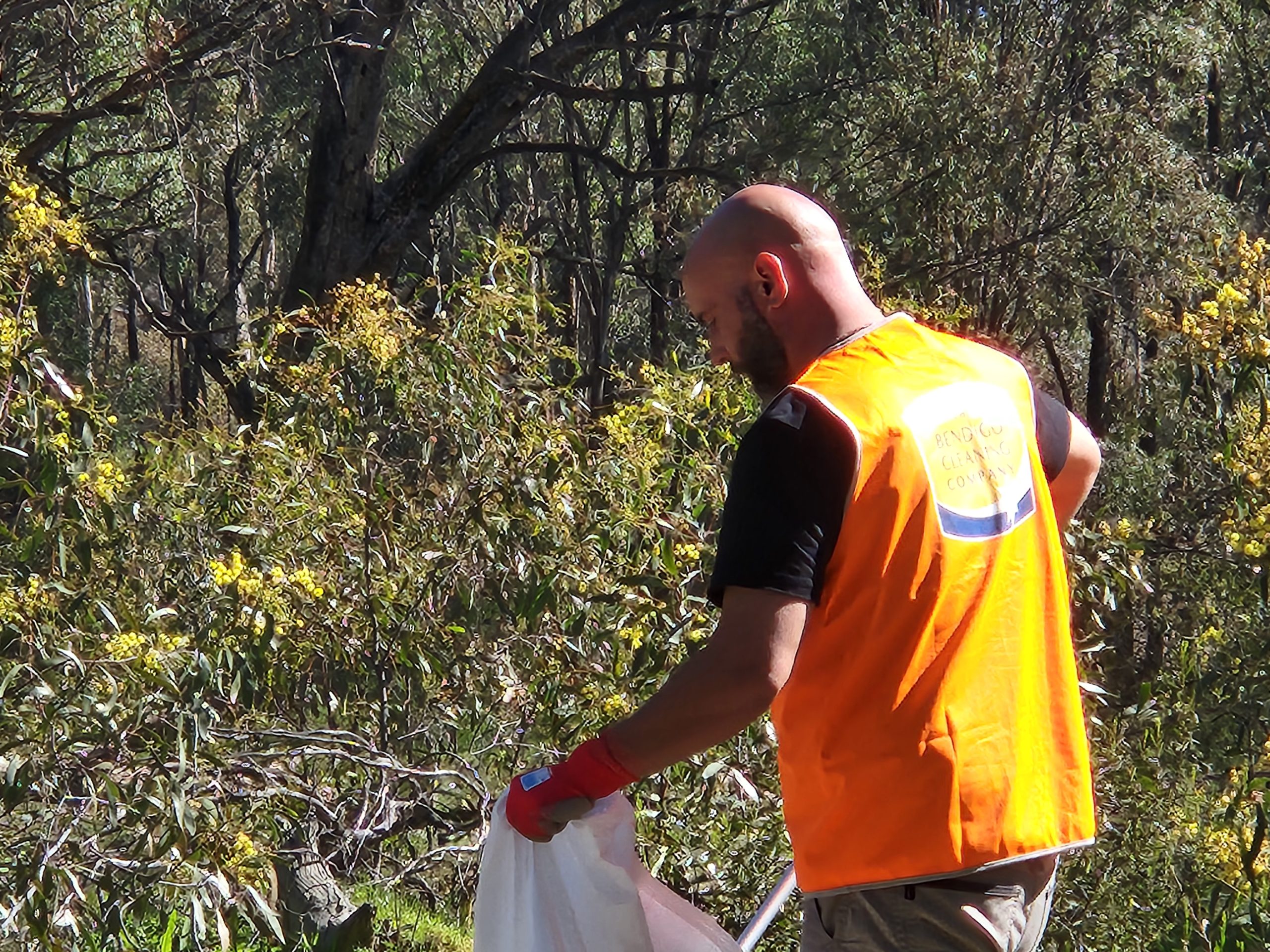 A member of The Bendigo Cleaning Company team collecting roadside rubbish at a community clean-up day