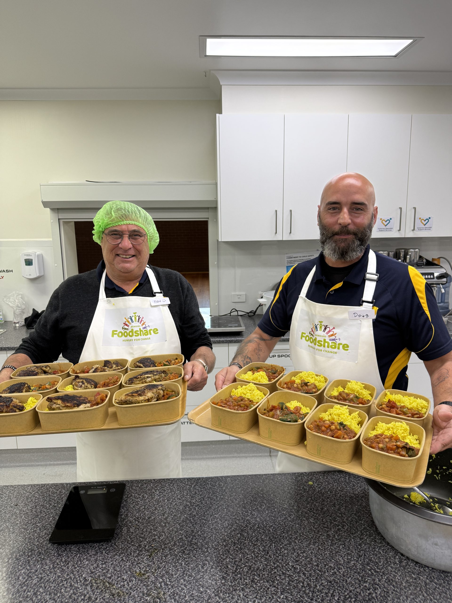 Two members of The Bendigo Cleaning Company team with meals they prepared at Bendigo Foodshare’s Cooking for a Change program